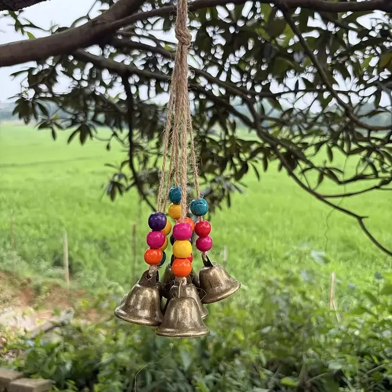 Handmade Bohemian Wind Chime, featuring jute rope with brass bells and colorful wooden beads, rings melodiously in the gentle breeze, adding natural romance to your home.