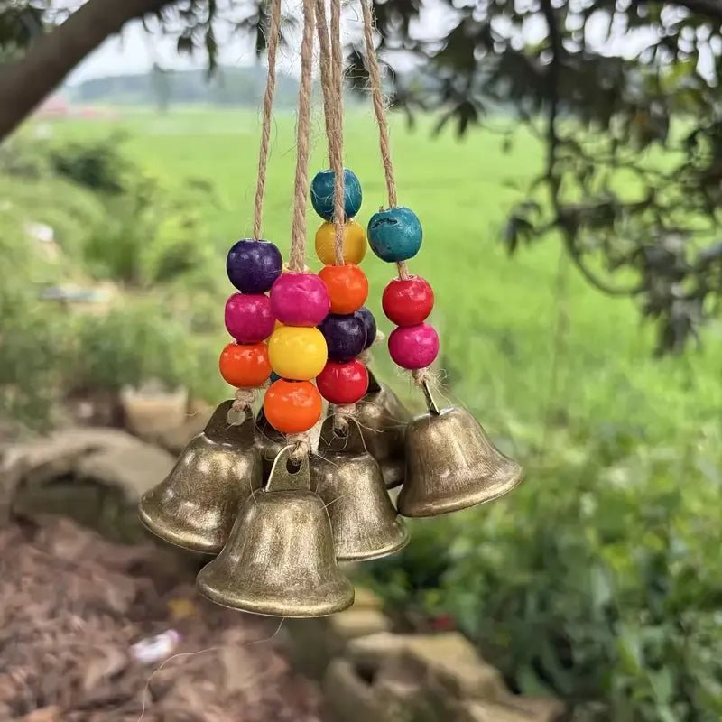 Handmade Bohemian Wind Chime, featuring jute rope with brass bells and colorful wooden beads, rings melodiously in the gentle breeze, adding natural romance to your home.
